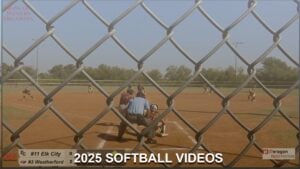 Elk City High School softball team playing against Weatherford, viewed through a chain-link fence during a 2025 game.